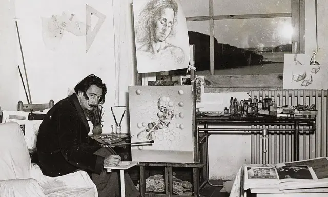 Salvador Dalí en su estudio, rodeado de sus icónicos cuadros, trabajando en una nueva obra surrealista.