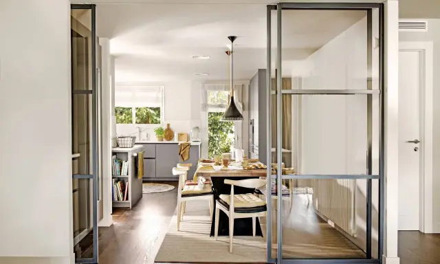Separación pared cristal cocina salón. Una puerta corredera de cristal divide la cocina del salón, creando un espacio abierto y luminoso.