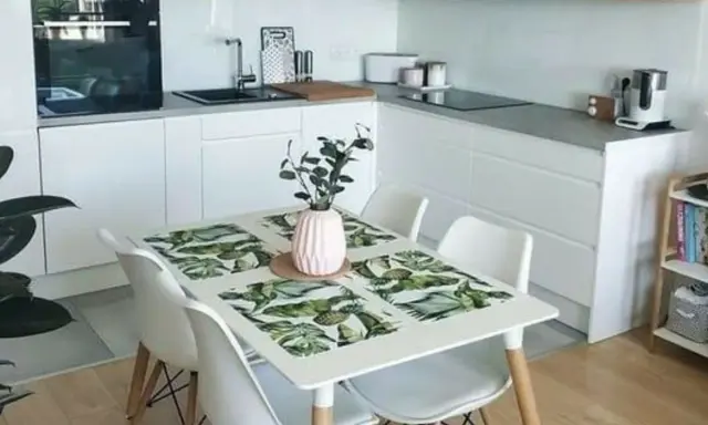 Cocinas pequeñas con mesa para comer, un espacio funcional y moderno con encimeras blancas, electrodomésticos integrados y una mesa con mantel tropical.