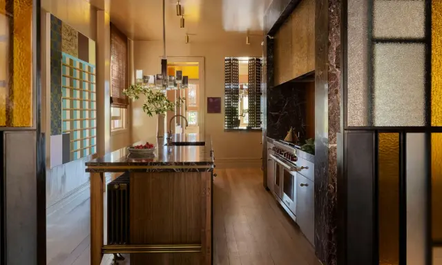 Cocina de lujo con isla de mármol, electrodomésticos de acero inoxidable y detalles en vidrio de colores. Una clara tendencia en cocinas modernas y sofisticadas.