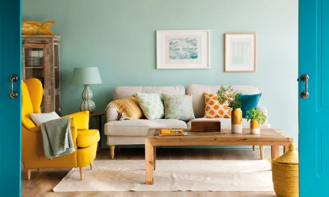 Un sillón amarillo vibrante y cojines con estampados alegres muestran los **colores que combinan con mostaza** en esta sala de estar acogedora.