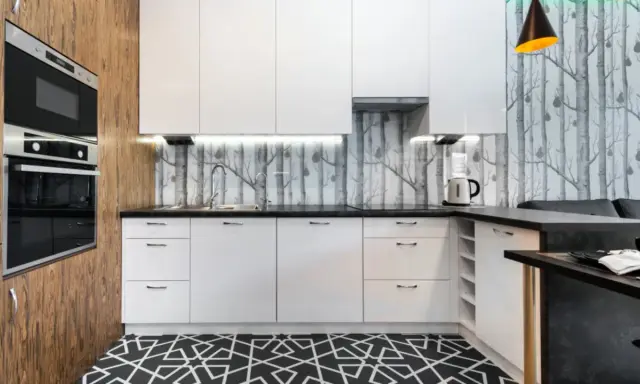 Cocinas modernas con papel pintado de árboles, gabinetes blancos y suelo geométrico.
