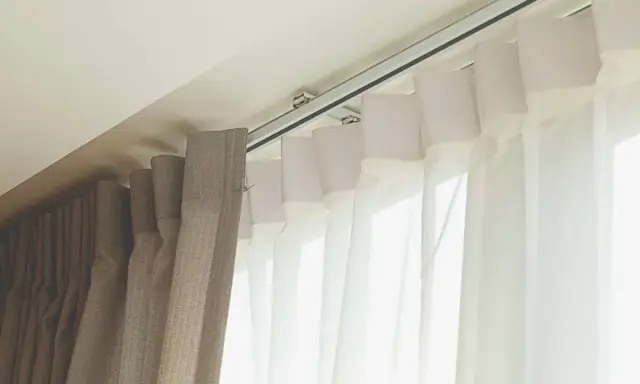 Detalle de rieles para cortinas, mostrando diferentes tipos de tela y su sistema de sujeción al techo.