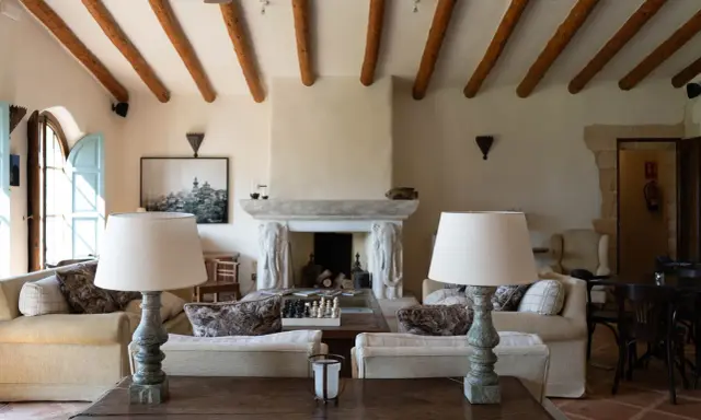 Acogedor salón comedor de casa de campo con vigas de madera, chimenea de piedra y sofás confortables.