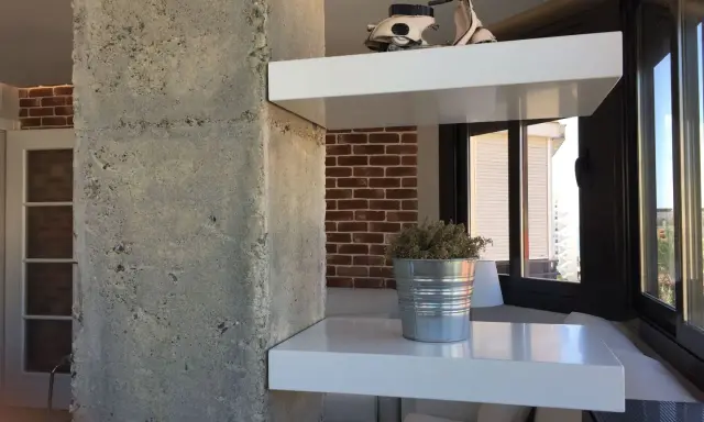 Ideas para decorar una columna en el salón: estantes blancos con Vespa y planta, ladrillo visto y hormigón.