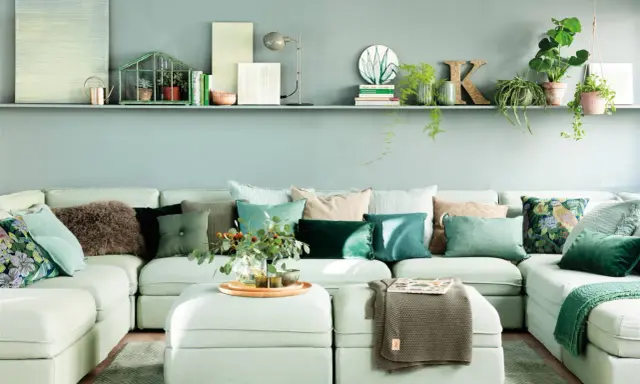 Sofá modular verde agua con cojines en tonos tierra y verdes, creando un ambiente sereno.