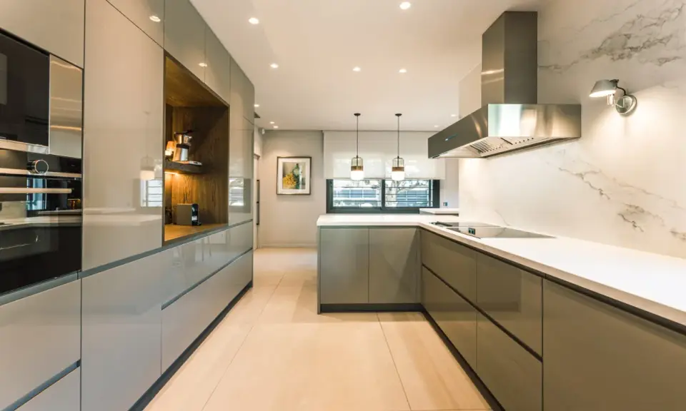 Elegantes diseños de cocinas modernas pequeñas, con gabinetes grises brillantes, encimeras blancas y electrodomésticos integrados.
