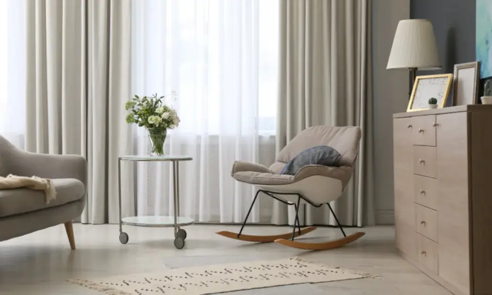 Elegantes cortinas de salón, mecedora beige y cómoda de madera. Las últimas tendencias en cortinas para tu salón.