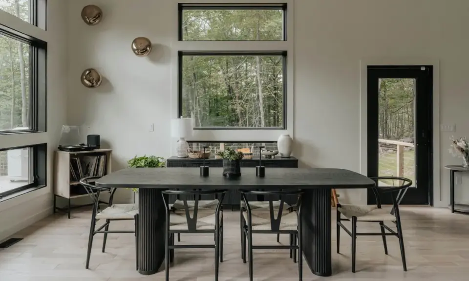 Salón moderno con mesa de comedor negra, sillas de madera y decoración de pared con esferas doradas.