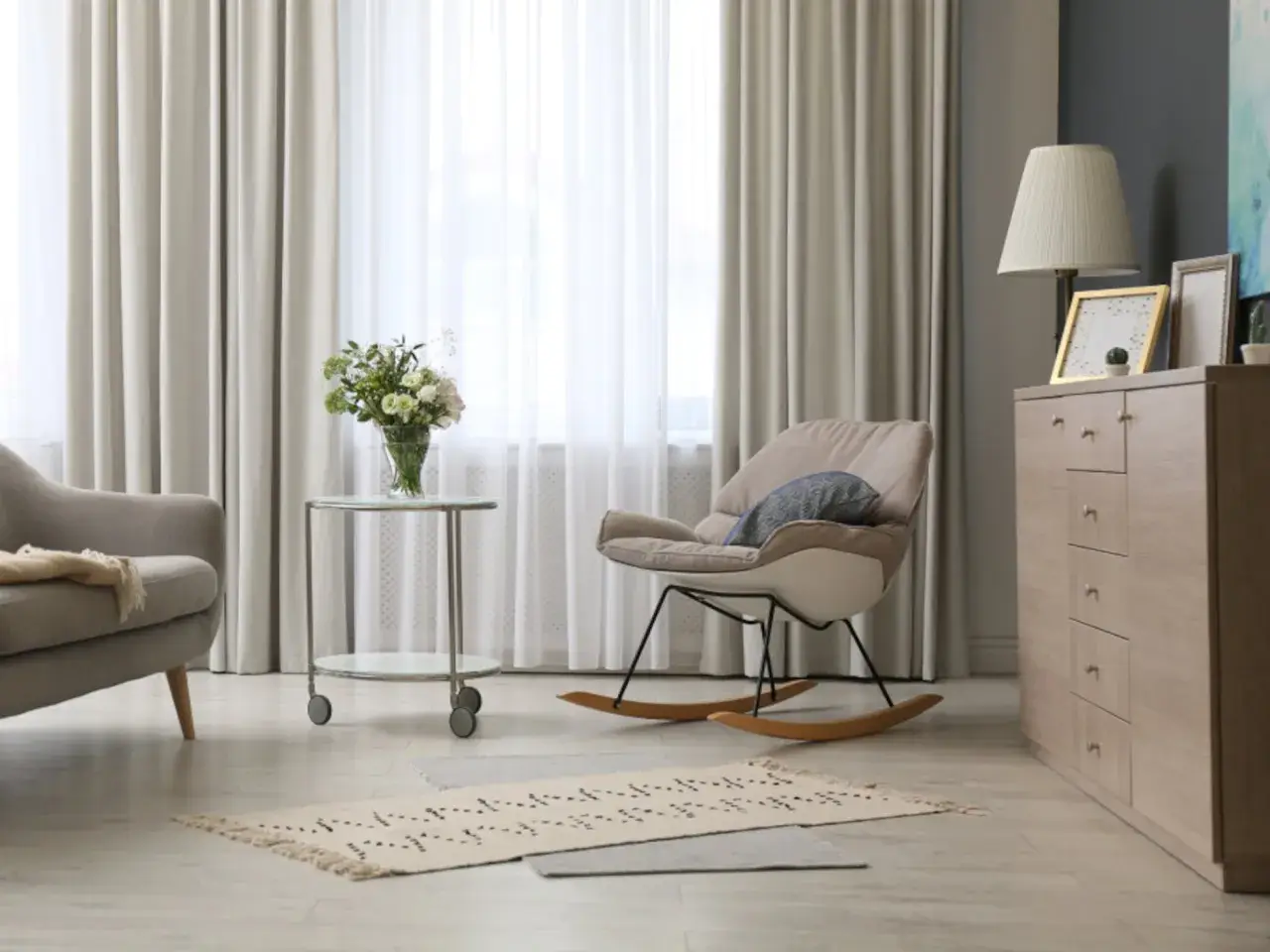 Elegantes cortinas de salón, mecedora beige y cómoda de madera. Las últimas tendencias en cortinas para tu salón.
