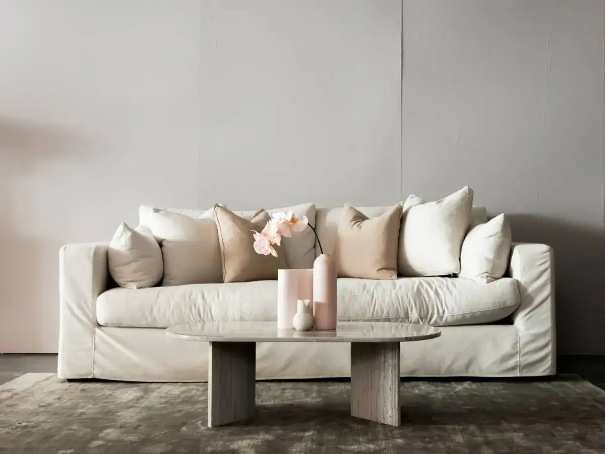 Sofá blanco con cojines en tonos neutros, una forma elegante de como colocar cojines en sofá para un look acogedor.