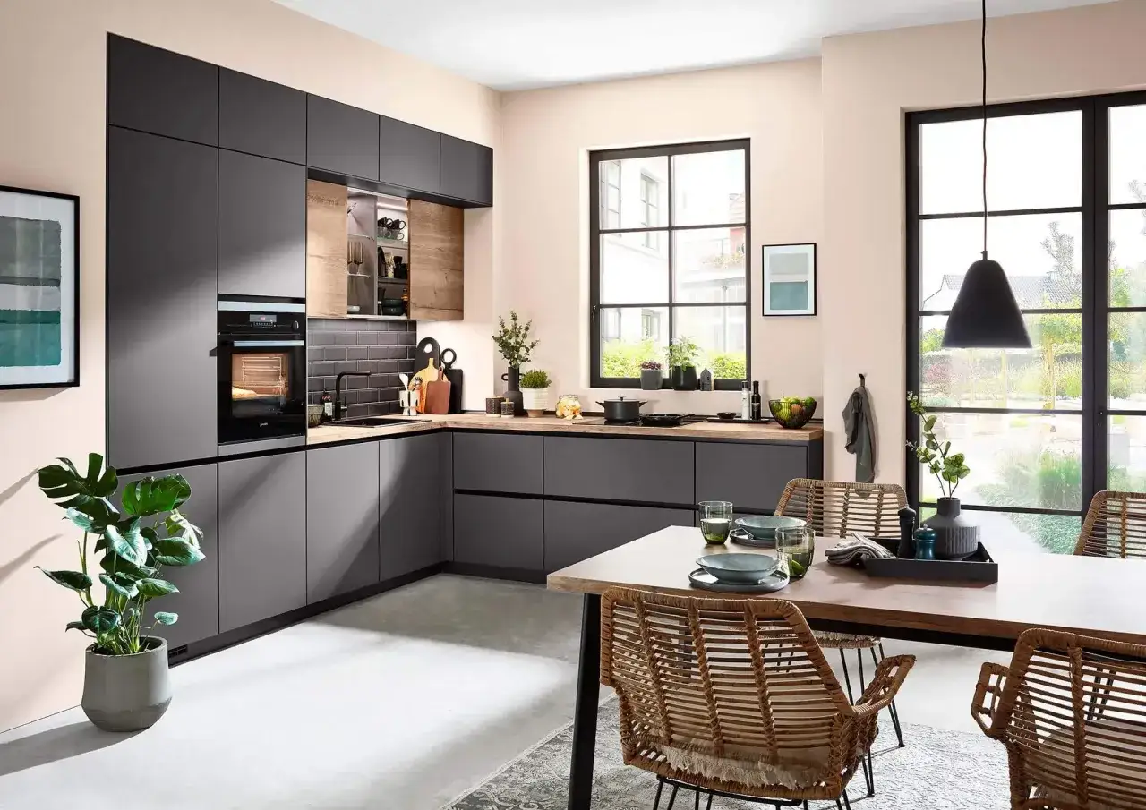 Moderna cocina en L con gabinetes grises, encimeras de madera y una isla central. Mesa de comedor con sillas de mimbre.
