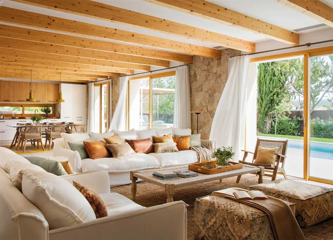 Salones colores neutros con sofás blancos, vigas de madera y vistas a piscina.