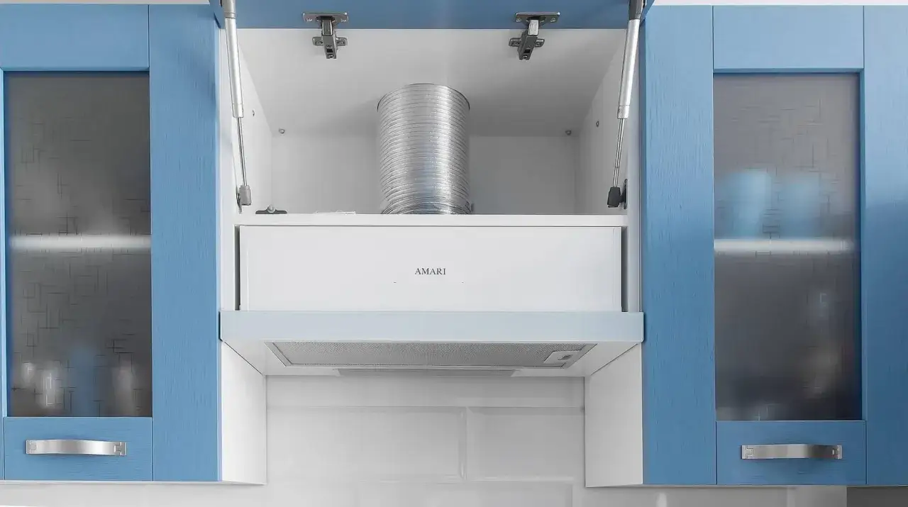 Detalles de como instalar una campana extractora decorativa: campana blanca AMARI, tubo de ventilación plateado y armarios azules.