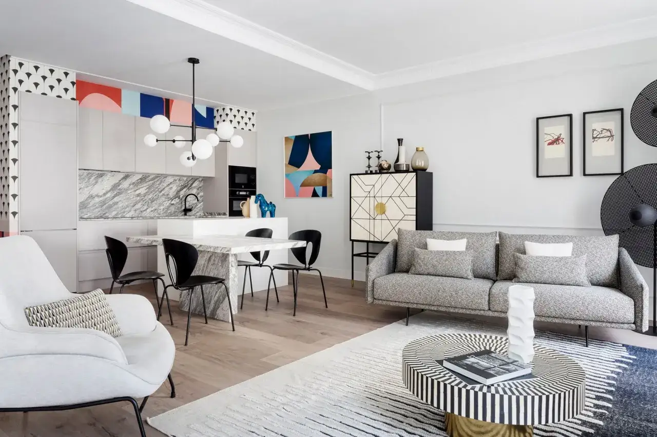 Moderna cocina americana y salón con muebles de diseño, arte abstracto y una lámpara escultural.