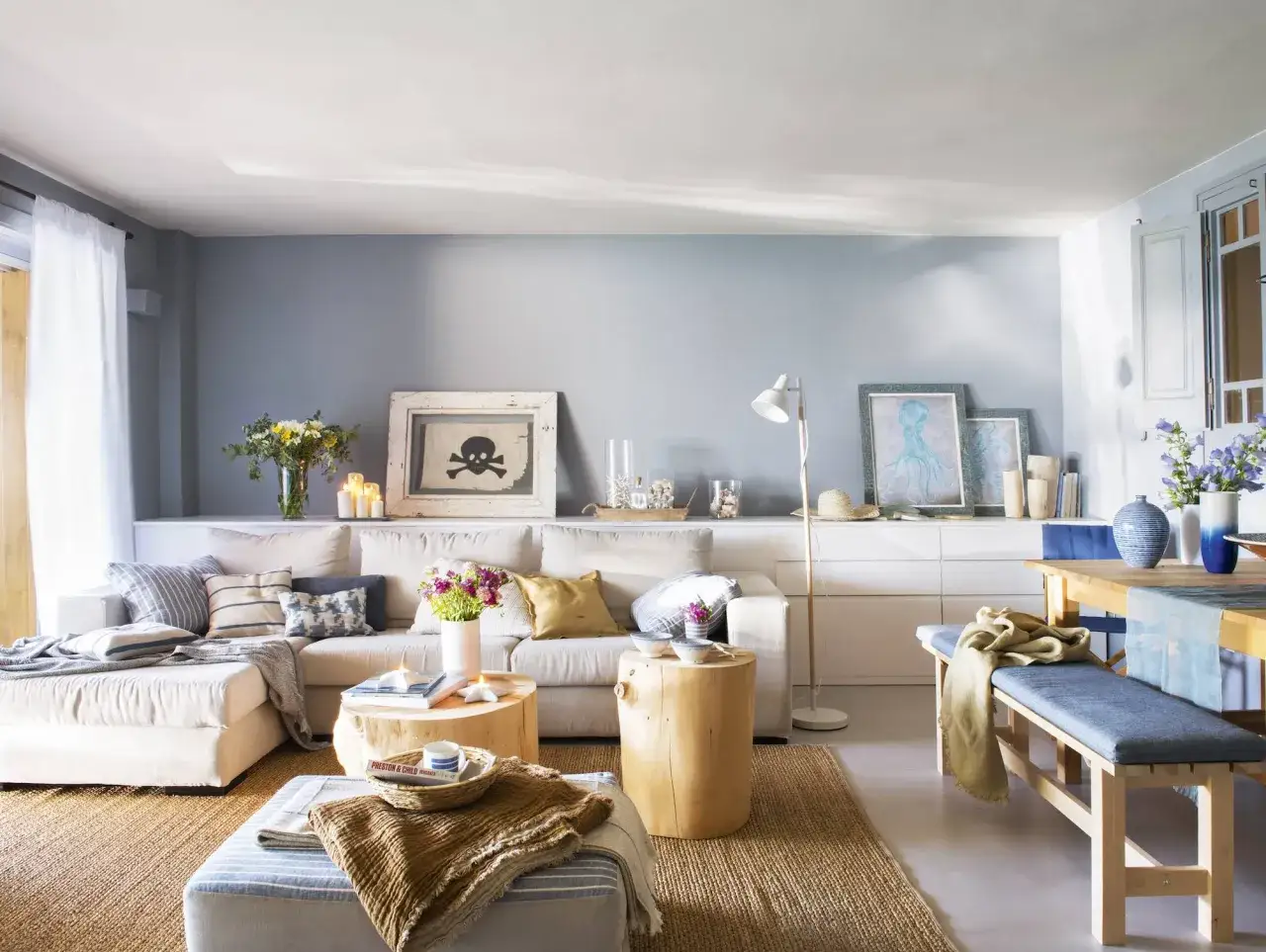 Sofá modular y banco de comedor con cojines de un suave y dusty blue. Decoración costera con calavera pirata y pulpo.