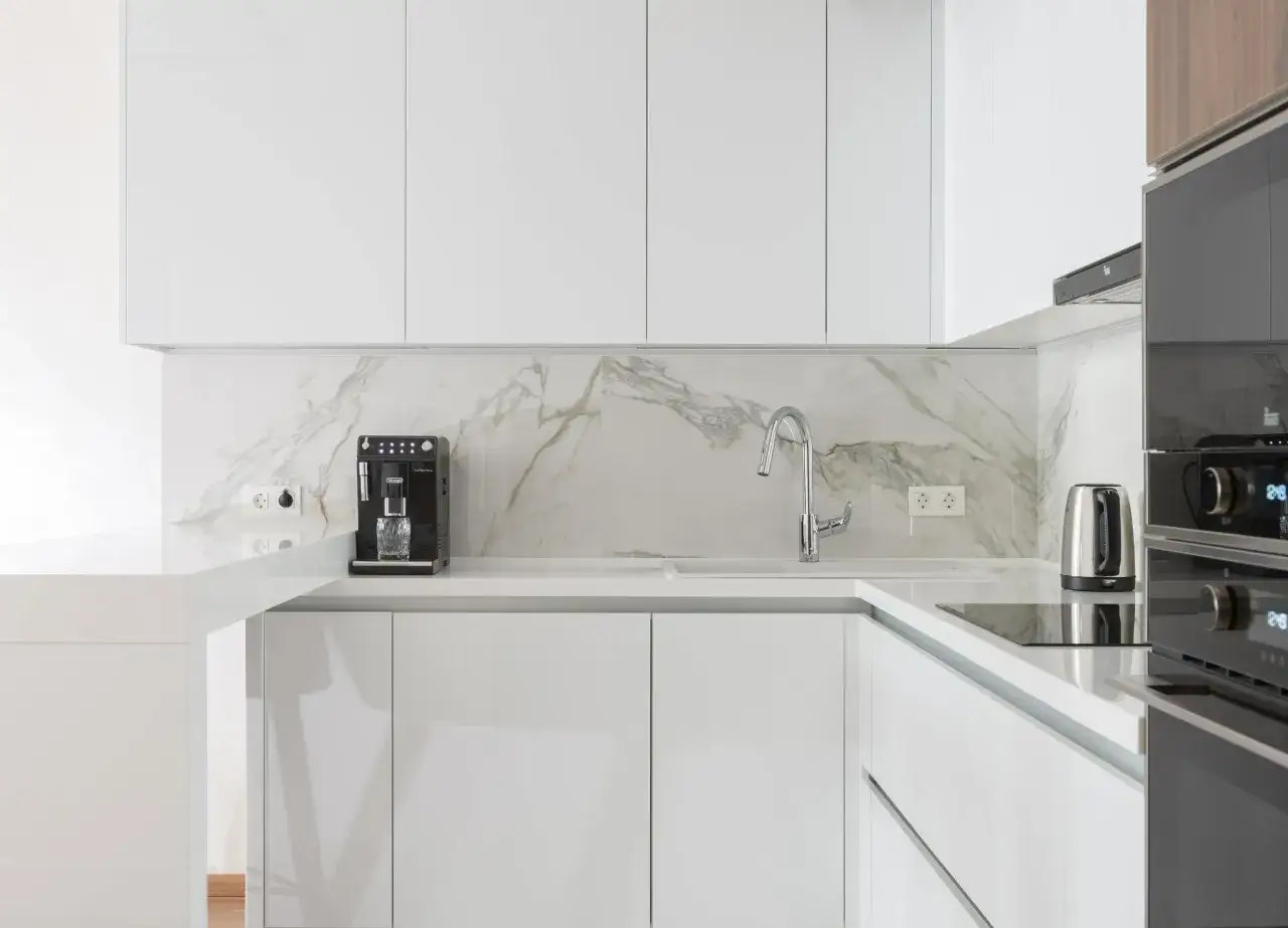 Cocinas blancas elegantes con encimeras de m&aacute;rmol, cafetera y hervidor.