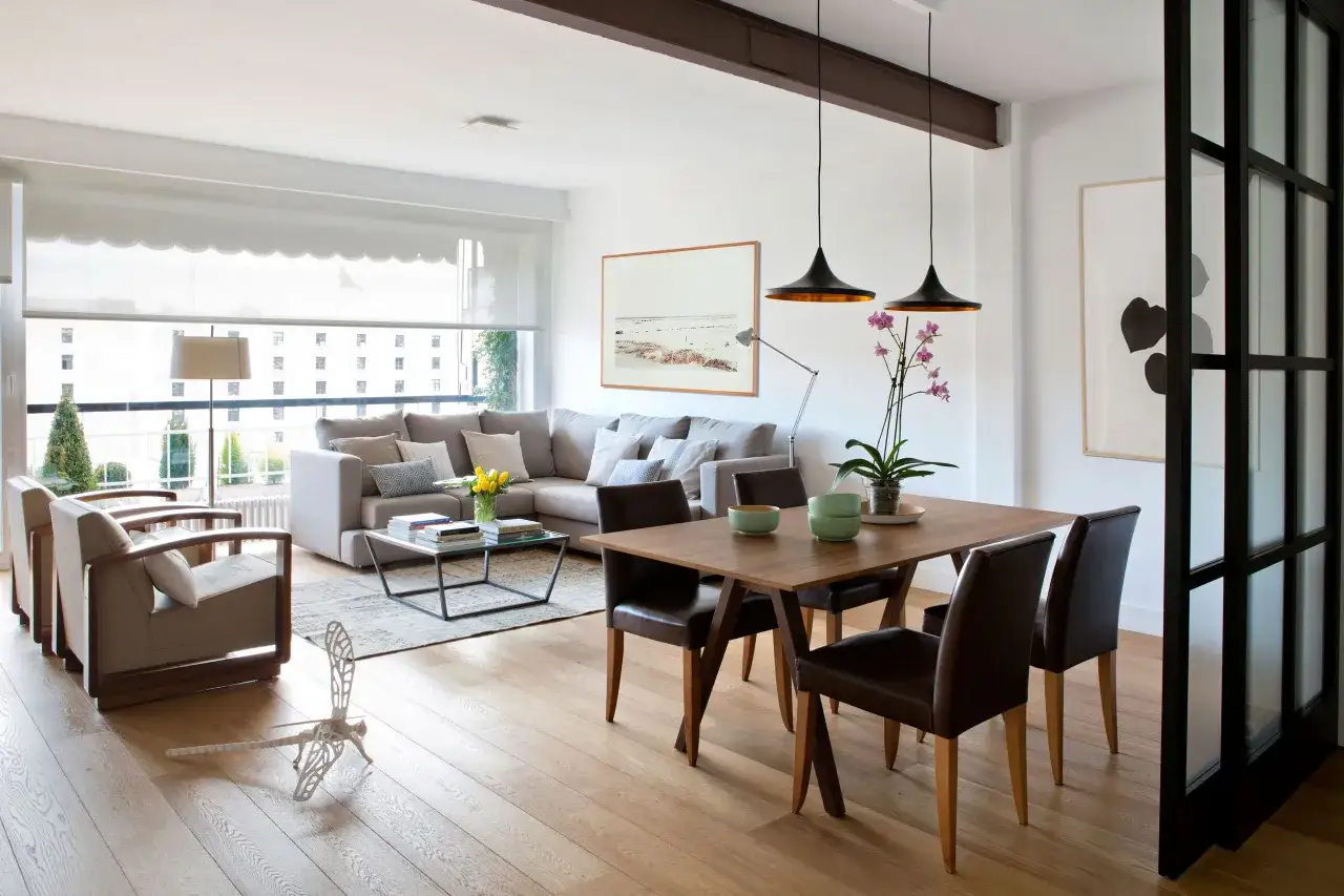 Salón moderno con sofá, mesa de comedor y sillas. La decoración, con plantas y cuadros, sigue principios de feng shui para crear armonía.