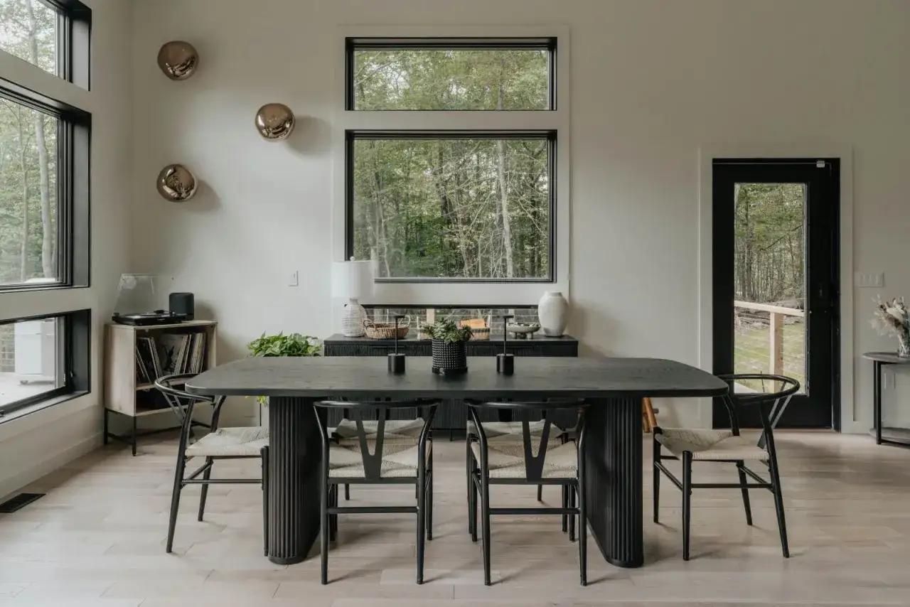 Ideas para como decorar una mesa de comedor moderna: mesa negra, sillas de diseño, centro de mesa minimalista y arte en la pared.