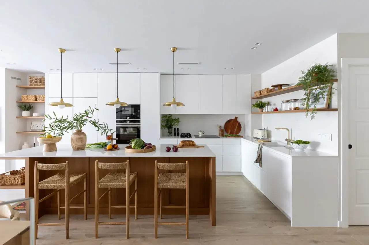 Cocina moderna y luminosa, un espacio de interior design studio con isla central de madera, taburetes de fibras naturales y electrodom&eacute;sticos integrados.