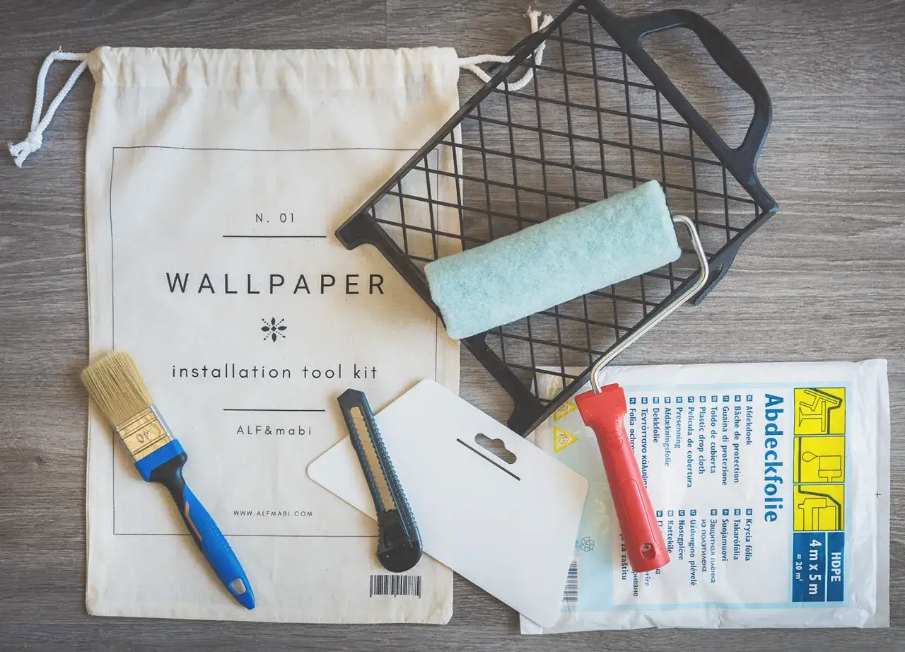 Kit de herramientas para saber como poner papel pintado: brocha, rodillo, c&uacute;ter y pl&aacute;stico protector.