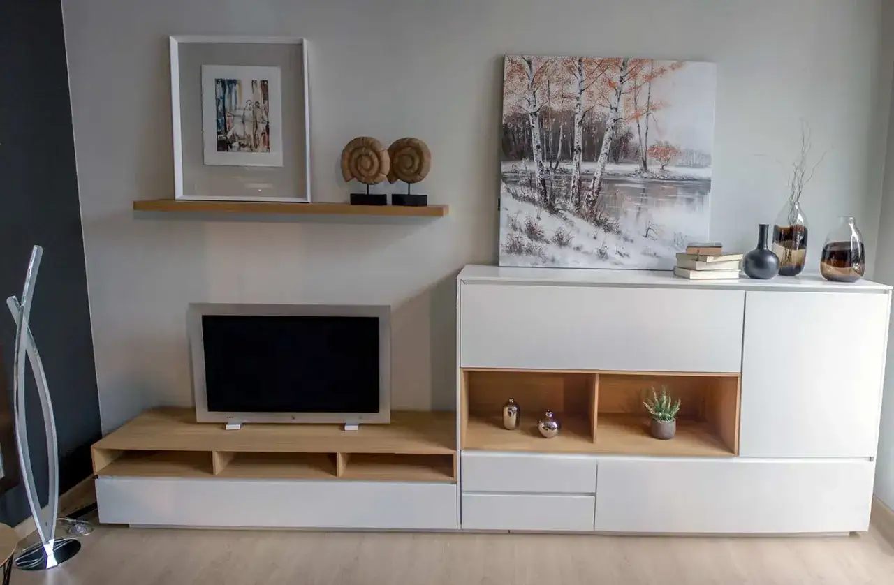 Salones blancos y madera, con un televisor, cuadros y adornos.