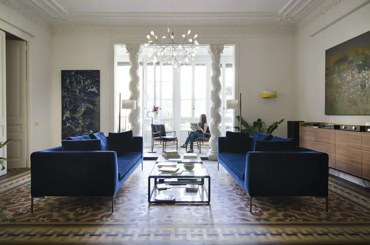 Ideas para decorar una columna en el salón: dos sofás azules flanquean una chimenea con una mujer leyendo.