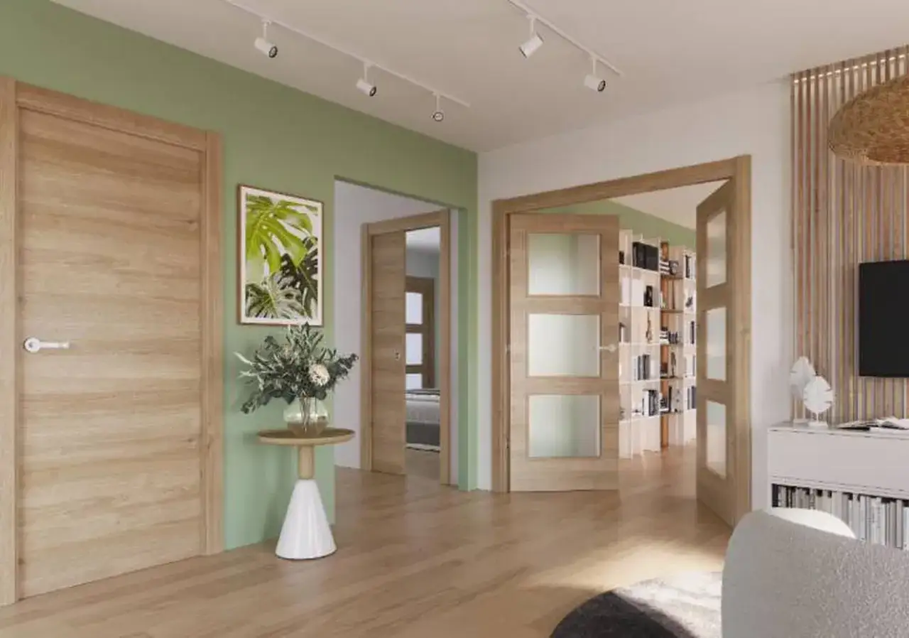 Puertas de roble con marcos de madera clara y paredes verde menta. Un pasillo con m&aacute;s puertas de roble y una estanter&iacute;a llena de libros.