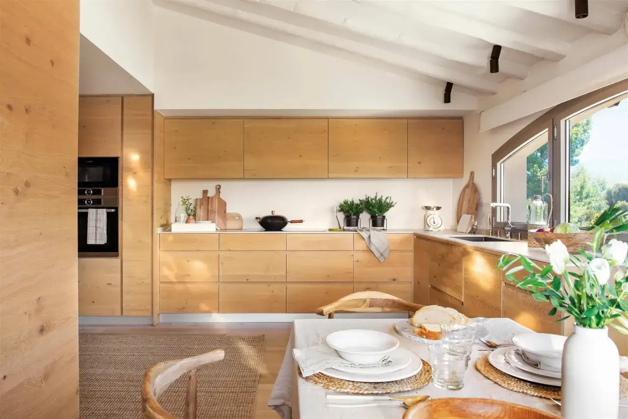 Cocina de madera clara, ideal para decorar piso moderno y elegante. Mesa puesta con estilo rústico y luz natural.