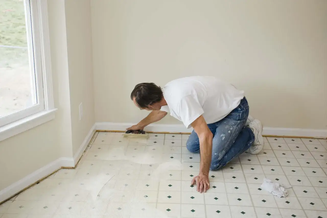 Hombre instalando suelos para cocinas sin obras, aplicando adhesivo sobre el suelo existente.
