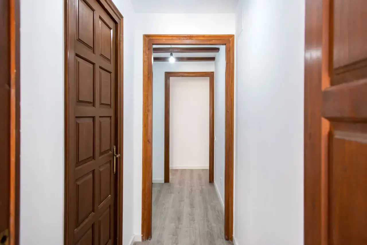 Pasillo con puertas de madera oscura y marcos de madera. Se ven que puertas de interior se llevan, con un estilo clásico y elegante.