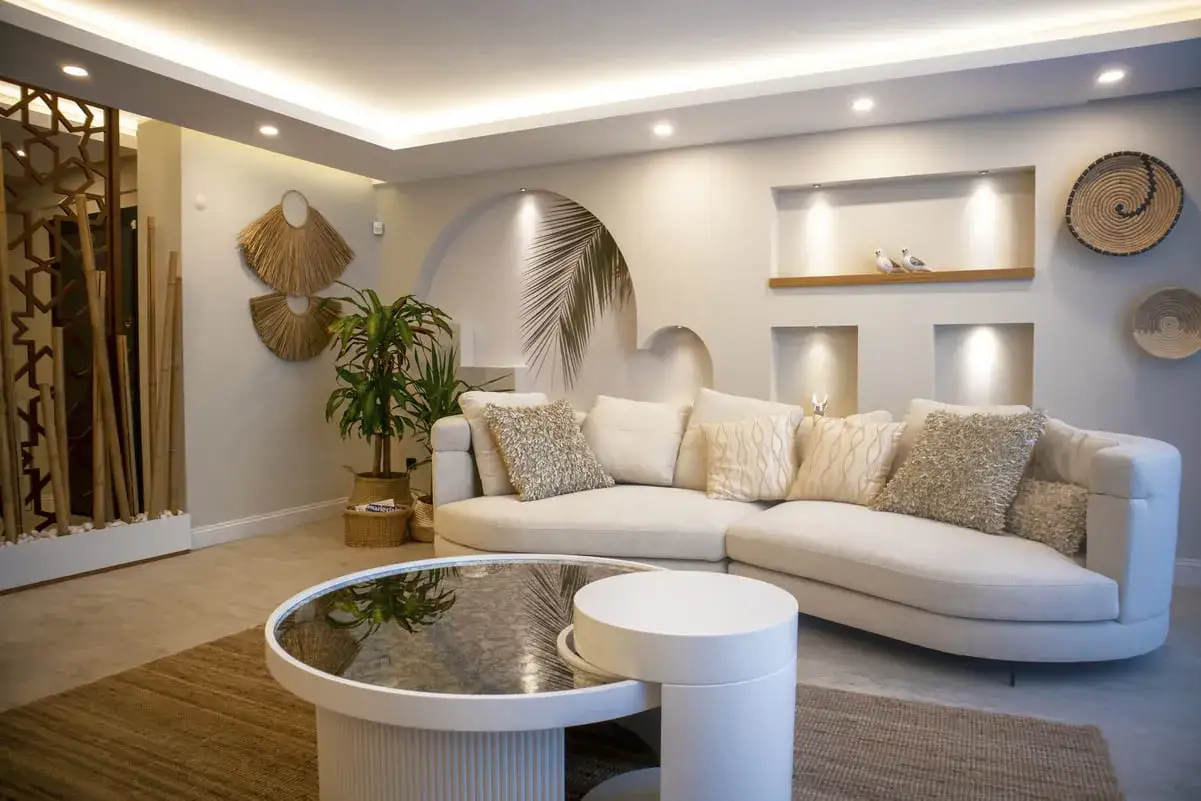 Un salón moderno y acogedor, ideal para aprender como iluminar un salon. Sofá curvo, mesa de centro redonda y decoración natural.