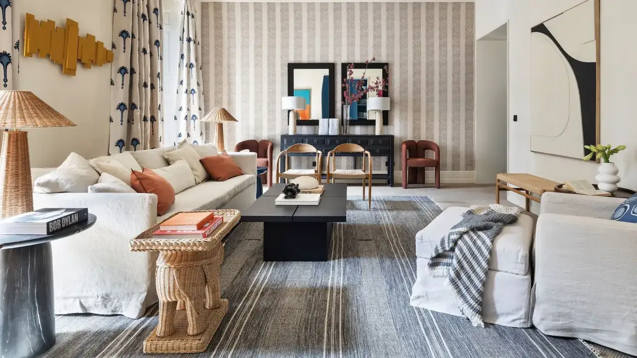 Elegante sala de estar con sofás blancos, mesa de centro negra y alfombras de rayas que complementan la decoración de la casa.