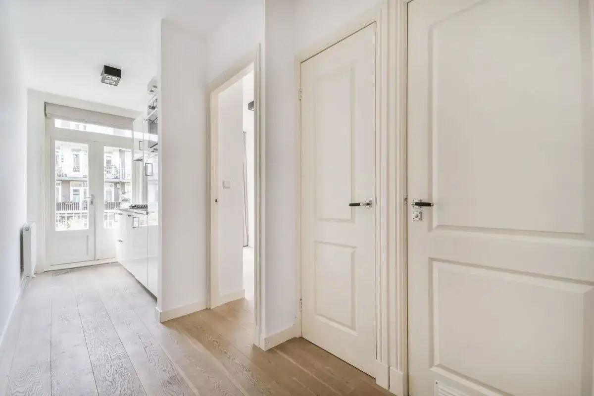 Pasillo blanco con varias puertas, ideal para cambiar puertas de casa y dar un aire nuevo.