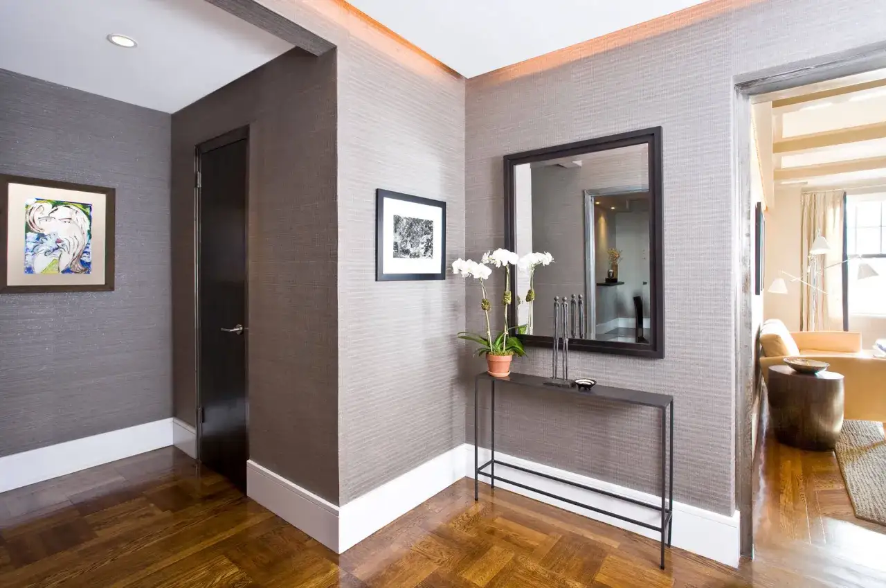 Pasillo moderno con suelo de parquet, papel texturizado y rodapiés blancos que realzan las tendencias rodapiés modernos.