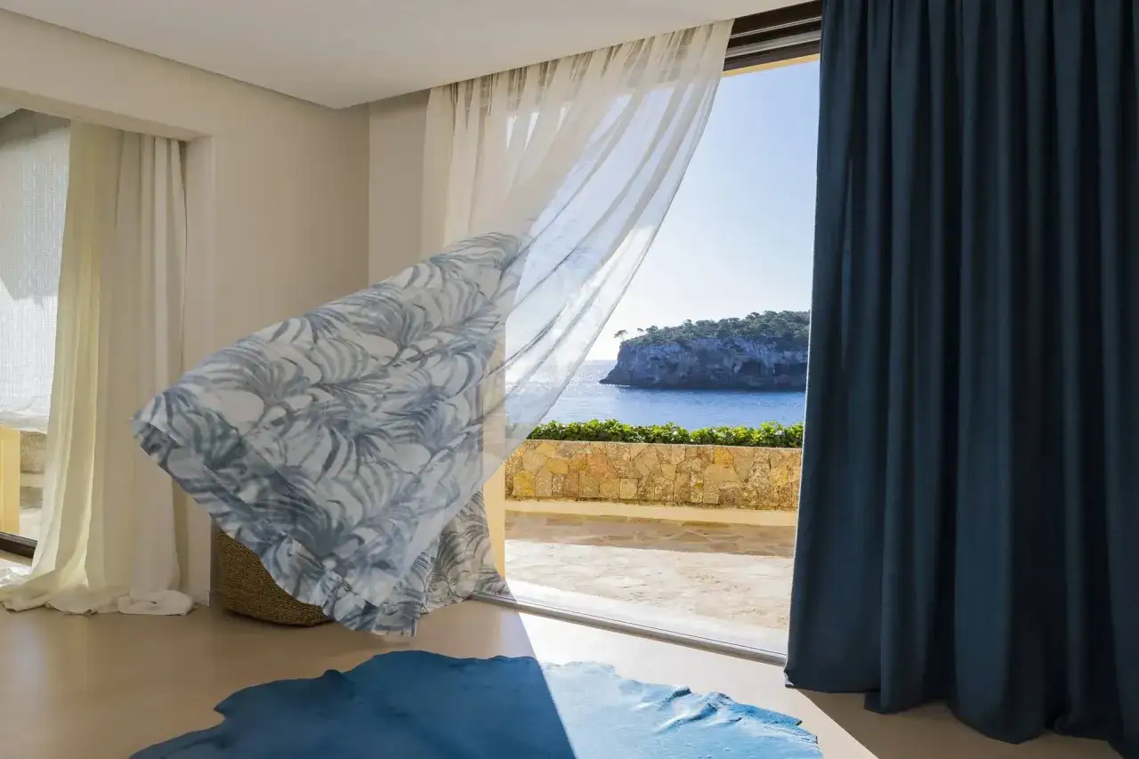 Cortinas Bandalux ondean con la brisa marina, revelando un paisaje costero idílico.