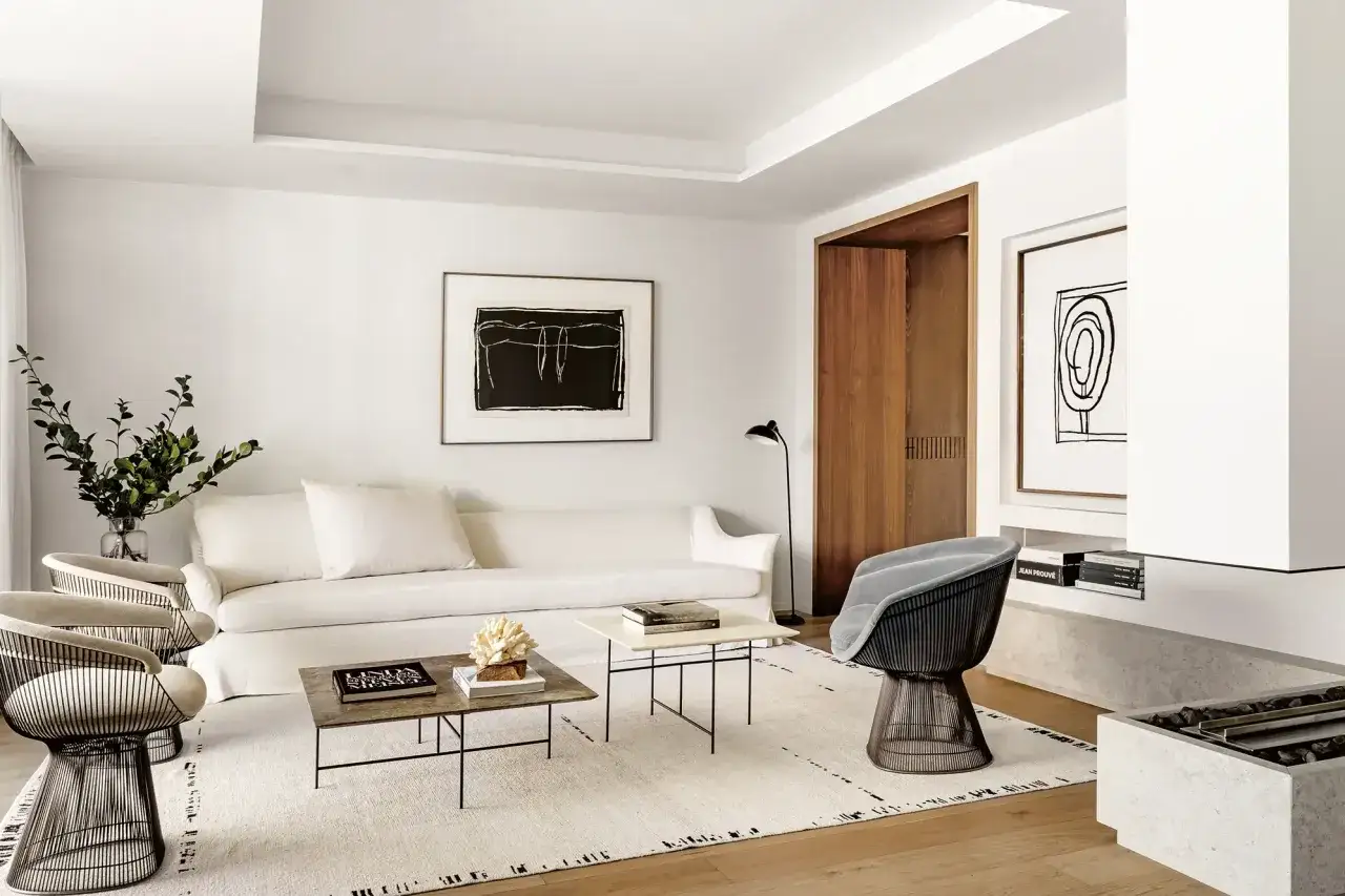 Elegante salón con sofá blanco, sillas de diseño y alfombras de diseño que aportan calidez y estilo.