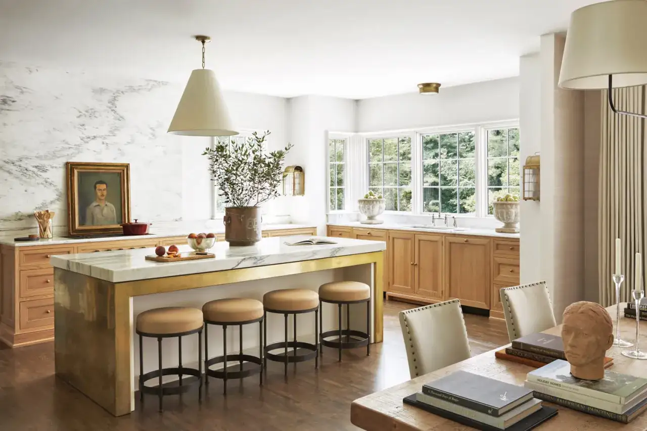 Cocinas sin muebles altos, con isla central de mármol y taburetes. Encimeras de madera y pared de mármol con retrato.