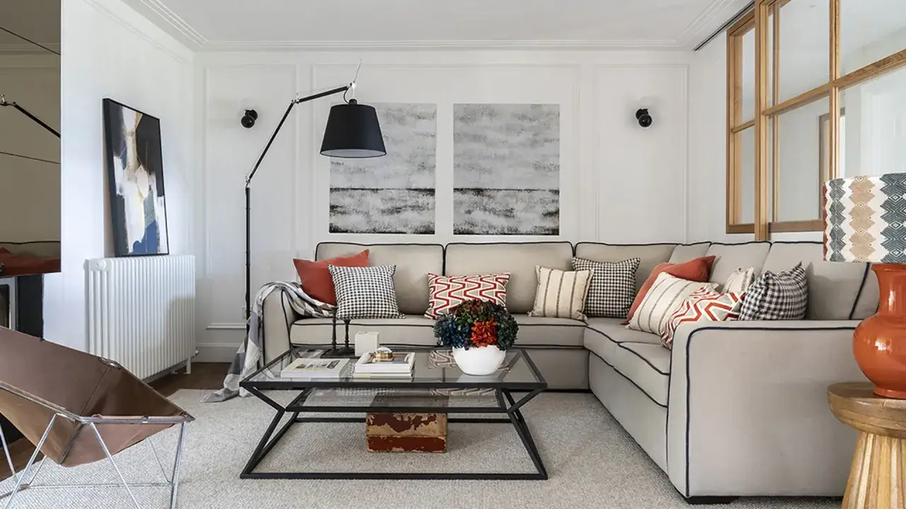 Sofá rinconera gris, cojines variados y mesa de centro de cristal. Un espacio acogedor para decorar salón.
