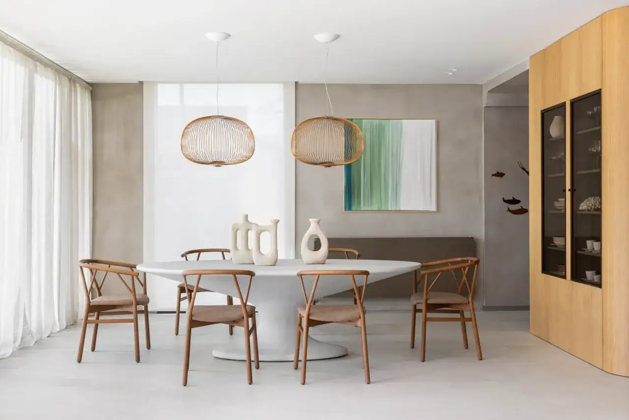 Ideas para decorar un comedor sencillo: mesa ovalada, sillas de madera, lámparas de alambre y arte abstracto.