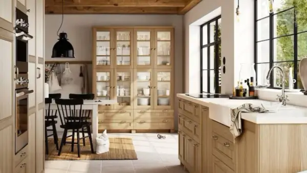 Cocinas rústicas modernas con gabinetes de madera clara, vitrinas llenas de vajilla y una isla con fregadero.