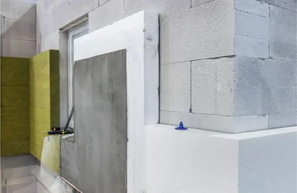 Construcción de fachada con bloques de hormigón, lana de roca y poliestireno expandido, demostrando la aplicación de materiales aislantes.