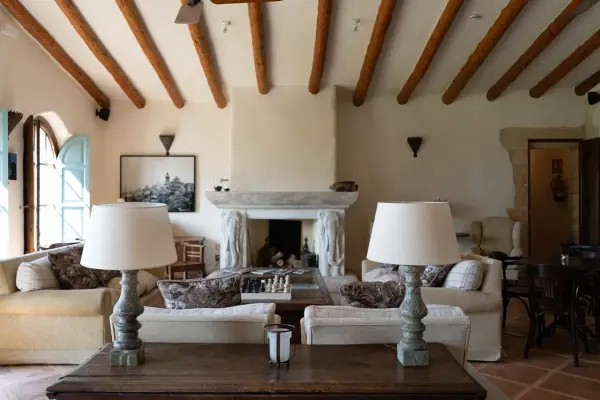 Acogedor salón comedor de casa de campo con vigas de madera, chimenea de piedra y sofás confortables.