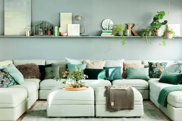 Sofá modular verde agua con cojines en tonos tierra y verdes, creando un ambiente sereno.