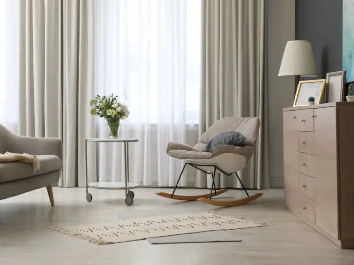 Elegantes cortinas de salón, mecedora beige y cómoda de madera. Las últimas tendencias en cortinas para tu salón.