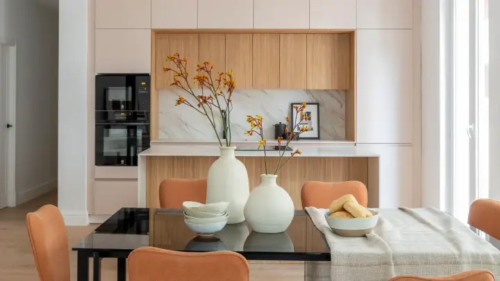 Dos jarrones con flores secas, cuencos apilados y un bol con panecillos son perfectos para poner encima de una mesa de comedor.