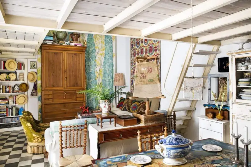 Un acogedor salón con estilo cottagecore, lleno de textiles coloridos, muebles de madera y objetos vintage.
