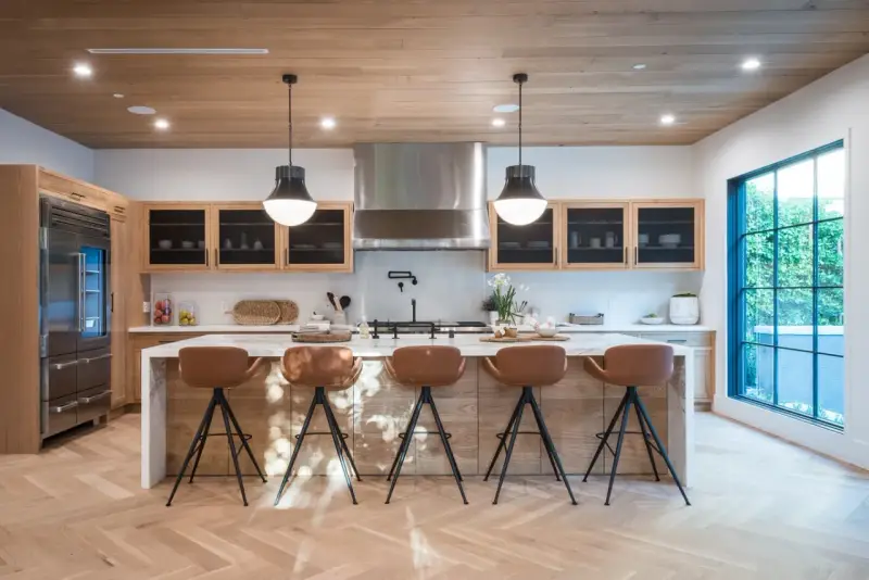 Cocina moderna con isla central y taburetes de cuero marrón. Las medidas del taburete son ideales para la altura de la isla.
